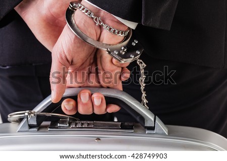 Businessman wearing a suit with a secure suitcase attached with handcuffs