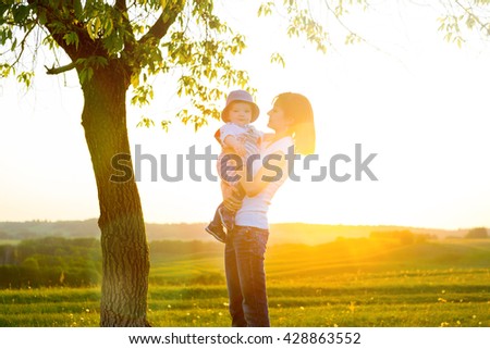 Portrait of picture of happy mother with baby on sunset background. Happy mother and son at sunset sunlight.