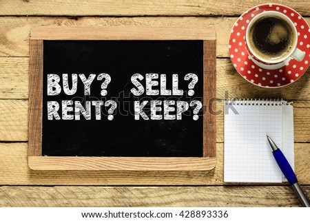 Buy? Sell? Rent? Keep? handwritten on blackboard with cup of coffee, notepad and pen on wooden table background
