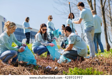 volunteering, charity, cleaning, people and ecology concept - group of happy volunteers with garbage bags cleaning area in park Royalty-Free Stock Photo #428931997