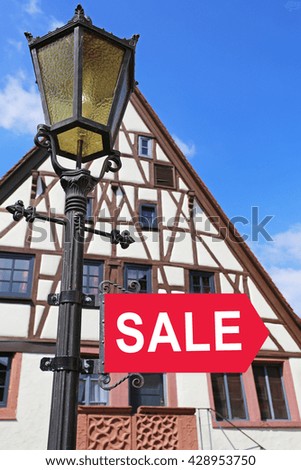  The word SALE on pointer on Antique lantern on the  old German houses background, focus on the pointer