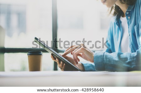 Work process modern Studio.Young Girl Hipster working wood table with new freelance Business Startup. Using Digital Tablet,Touching Screen. Horizontal photo.Film effect. Blurred background