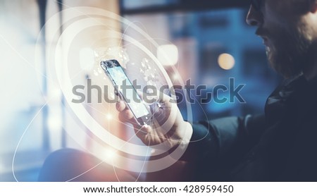 Closeup photo businessman relaxing modern loft office.Man sitting in chair at night.Using contemporary smartphone,blurred background. Digital Connections World Wide Interfaces.Horizontal,film effect