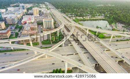 Aerial view massive highway intersection, stack interchange with elevated road junction overpass at late afternoon in Houston, Texas. This five-level freeway interchange carry heavy traffic, panorama.