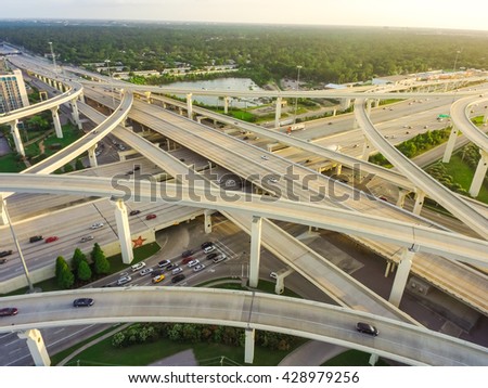 Aerial view massive highway intersection, stack interchange with elevated road junction overpass at late afternoon in Houston, Texas. This five-level freeway interchange carry heavy rush hour traffic.