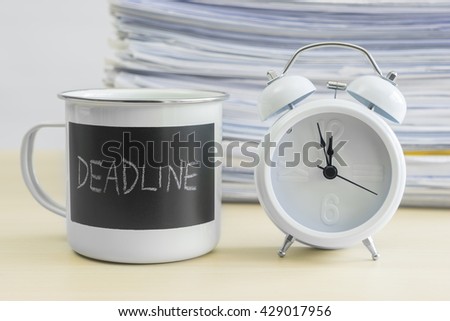 Meet your deadline words on coffee mug with alarm clock and stack of papers on table