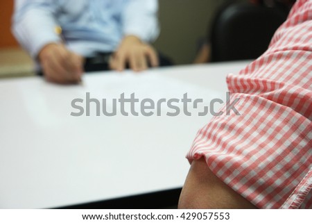 Close-up of business meeting, Two businessmen discussing a deal and signing a contract on white table, with close up waiting person and the far blurred decision-makers person in the meeting room