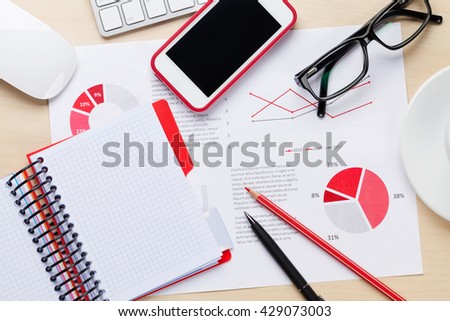 Office desk workplace with smart phone, charts and coffee on wooden table. Top view with copy space