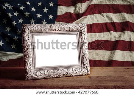 Vintage photo frame on wooden table over grunge America flag background, vintage style