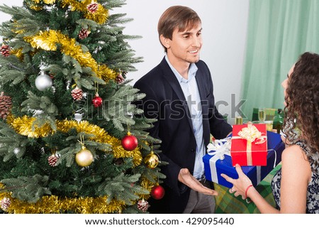 Happy young woman presenting gift to smiling man at table during romantic Christmas dinner
