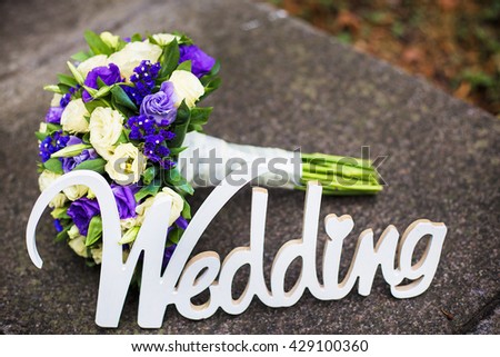 Word wedding and bridal very peri bouquet lying on the pavement