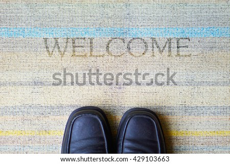 Welcome carpet with leather shoes on it. 