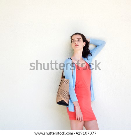 Portrait of a stylish young woman carrying a purse with her hand in her hair