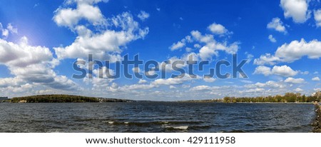 breathtaking scenery. many fluffy clouds in the blue sky over the water. hectic urban lake. panorama