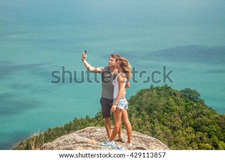 young couple of travelers  is doing selfie on a hill overlooking the sea