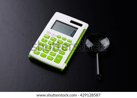 Calculator with a magnifying glass on a black background