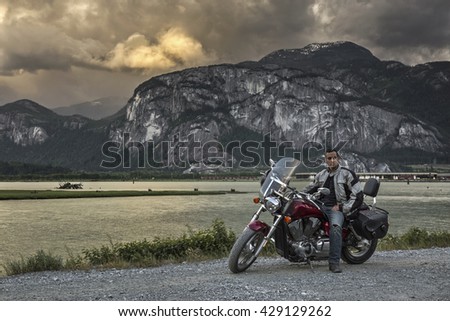 Rider on a motorcycle with Chief Mountain as the background. Taken in Squamish, British Columbia, Canada, on a cloudy sunset