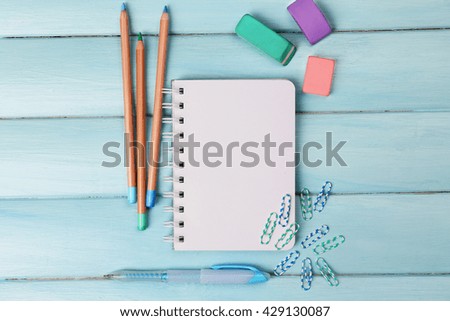 Office set with notebook, colored pencils and erasers on blue background