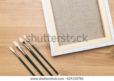 Top view of wooden desktop with a set of brushes and picture frame. Mock up