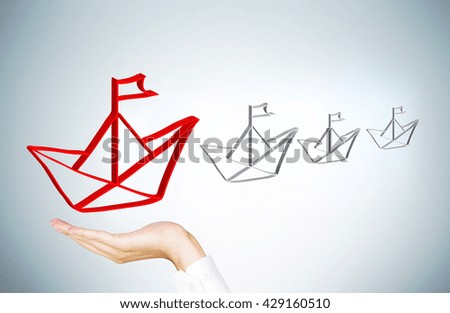 Leadership concept with businessman hand holding red paper ship icon