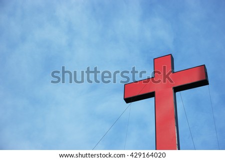 a real red cross or religion symbol cross shaped over a blue sky with clouds background as symbolic to God, Christ, Christianity, religious, faith, holy, spiritual, Jesus, belief or resurection