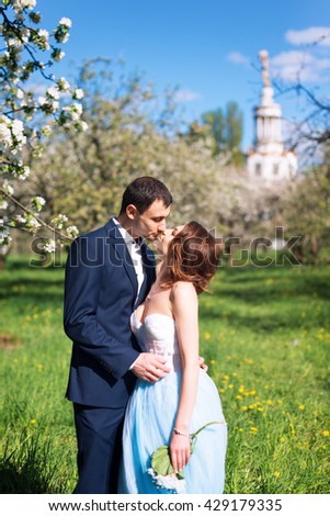 Groom and bride together, wedding couple. Young couple kissing in blooming spring garden. Love and romantic theme