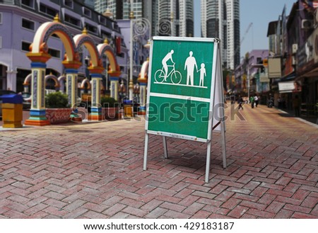 A green traffic sign for pedestrian and bicyclist against an urban city environment for the concept: Urban Pedestrian Walkway.