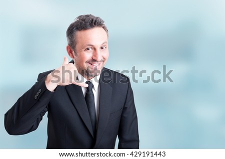 Joyful young salesman doing a call me gesture with hand as successful business concept with copyspace