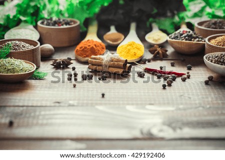 Beautiful colorful spices in spoons and bowls with lettuce, dill and Basil on an old wooden brown table. Free space for your text