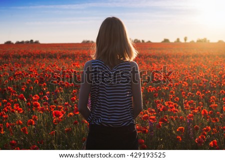 Woman at blooming poppy field. Sunset