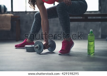 Body and mind workout in loft fitness studio. Closeup on fitness woman taking dumbbell from the floor in urban loft gym Royalty-Free Stock Photo #429198295