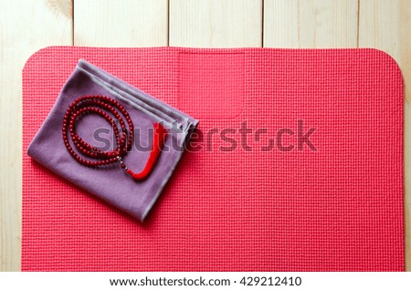 Accessories for yoga and meditation. Open mat and mala beads on wooden background with copyspace.