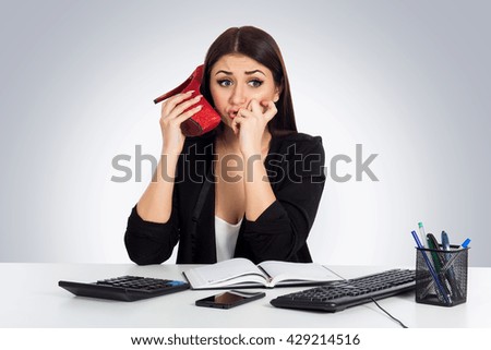 Young business woman using a shoe like a telephone holding it near her face and talking