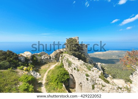 Tower with walls of the Kantara Castle located on a peak of Kyrenia mountains on Cyprus island with blue Mediterranean Sea on background.
