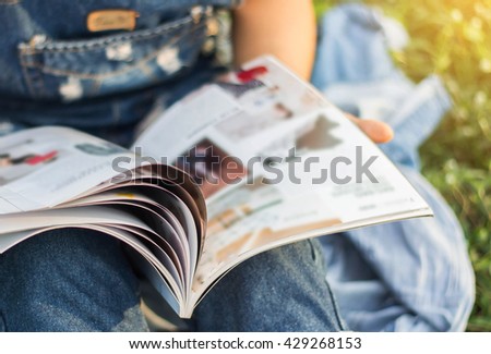 Woman reading a magazine blur in garden.