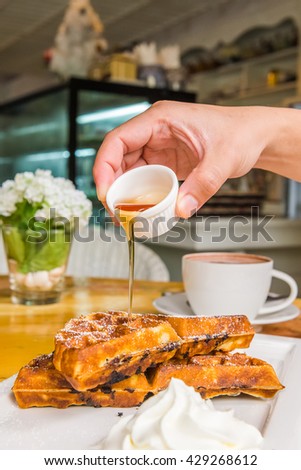 Poured a sweet honey to sweet pancakes with cream on wooden table and cap coffee background