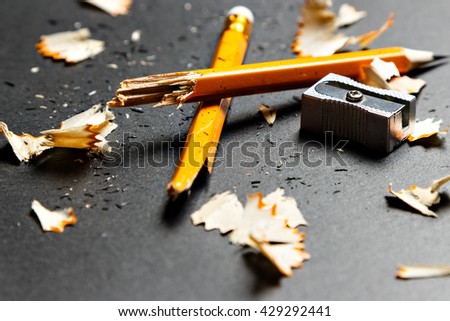 Broken pencil with metal sharpener and shavings on black background. Horizontal image. Royalty-Free Stock Photo #429292441