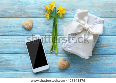 Gift box with yellow daffodils on wooden background