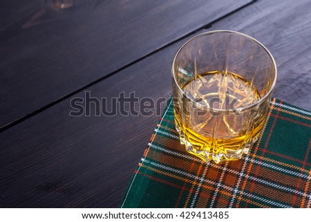 Glass of Scotch whisky on a traditional tartan cloth on a wooden table Royalty-Free Stock Photo #429413485