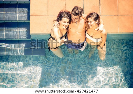 Group of friends taking selfie in a swimming pool - Young people relaxing and having fun on a summer vacation