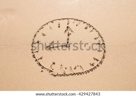 Time concept - Picture of a clock face on sandy beach.