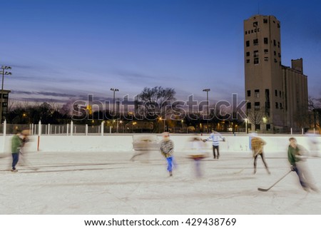 A Wide Action Shot of Blurred Hockey Players at a Public Park at Dusk in Winter 