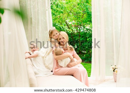 Beautiful young mother with three daughters Happy family of mother with three daughters in the yard in stylish interior. Fashion style street portrait.