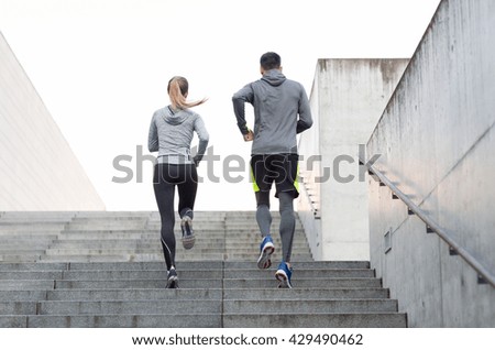 fitness, sport, people, exercising and lifestyle concept - couple running upstairs on city stairs Royalty-Free Stock Photo #429490462