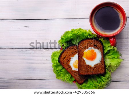 Cup of coffe and two fried eggs in toast on the salad.Top view .Free space.lunch