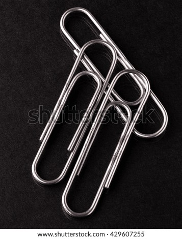 three metal paper clips on a black background