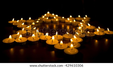 Many burning candles arranged into the shape of a star.