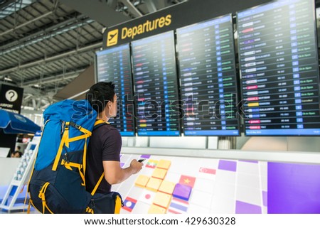 Young man with backpack in airport looking flight timetable Royalty-Free Stock Photo #429630328