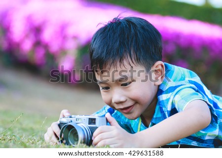 Asian boy taking photo by vintage film camera on blurred nature background at the day time.