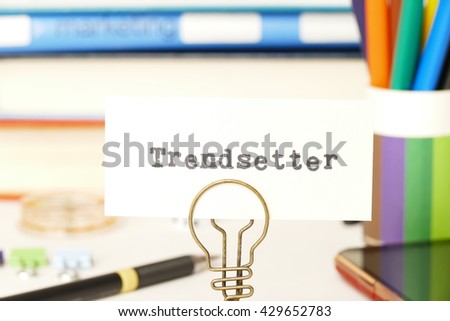 trendsetter word card  and photo holder  with background of textbook,  and  colored pencil.  it is a marketing concept of people who influence the market and society.